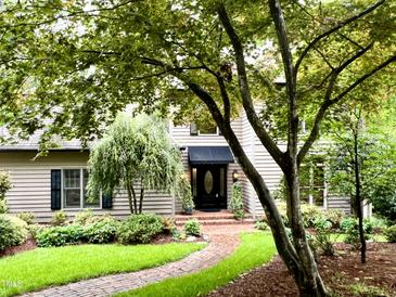 Charming home exterior with mature trees, landscaped yard, and inviting brick walkway at 1425 Bascomb Dr, Raleigh, NC 27614
