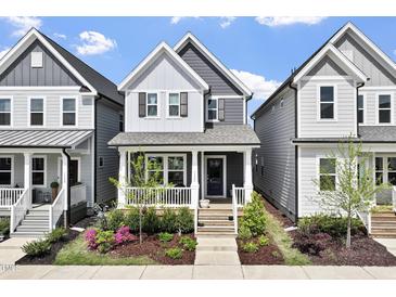 Charming two-story home featuring a covered front porch and beautifully landscaped yard with colorful flowers at 1526 Millrock Trl, Wendell, NC 27591