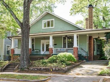 Charming green home with a inviting front porch framed by lush landscaping and mature trees at 1811 Park Dr, Raleigh, NC 27605