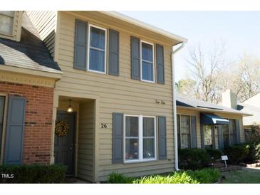Charming home with a tan exterior, gray shutters, and a brick accent wall near the front entrance at 26 Stonewall Way, Durham, NC 27704