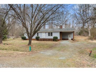 Quaint single story house with a gravel driveway, covered parking, and a brick chimney at 2670 Turner Rd, Mebane, NC 27302