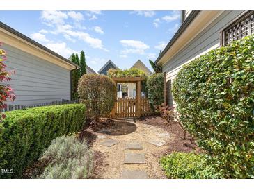 Landscaped backyard with a wooden gate and stepping stone pathway, offering a private and serene outdoor space at 379 Tobacco Farm Way, Chapel Hill, NC 27516