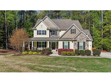 Charming two-story home with stone accents, lush landscaping, and inviting front porch at 64 Thousand Oaks Ct, Clayton, NC 27527