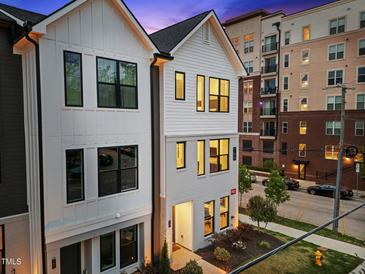 Modern, two-story home showcasing its bright exterior with black window trim and beautiful nighttime ambiance at 700 W North St # 101, Raleigh, NC 27603