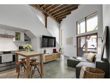 Bright living room featuring a modern table, wood beams, and a large window at 701 W Trinity Ave # 116, Durham, NC 27701