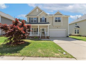 Charming two-story home with a well-manicured lawn, attached garage, and inviting front porch at 1127 Woodlands Creek Way, Apex, NC 27502