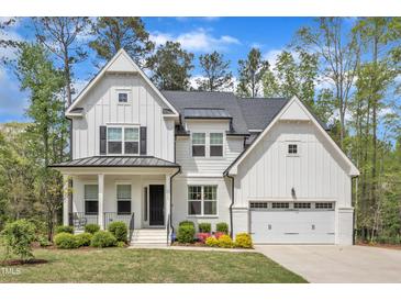 Stunning new construction farmhouse with a two-car garage, white siding, and a beautifully landscaped lawn at 2432 Spindle Ct, Raleigh, NC 27603