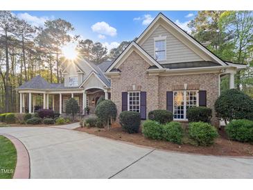 Beautiful brick home featuring manicured landscaping, a covered porch, and a curved driveway at 3016 Allansford Ln, Raleigh, NC 27613