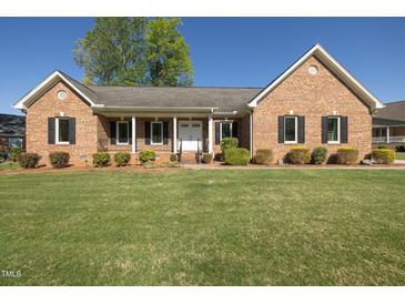Charming brick home featuring a well-manicured lawn, covered front porch, and mature landscaping at 627 Carraway Dr, Graham, NC 27253