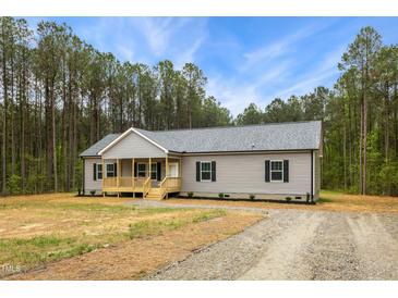 Charming single-story home featuring gray siding, black shutters and a covered front porch set on a large wooded lot at 6312 Briddle Dr, Wendell, NC 27591