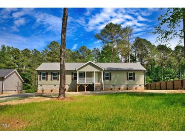 Charming ranch home with green siding, white trim, and a welcoming front porch in a lush yard at 7120 Guess Rd, Hillsborough, NC 27278
