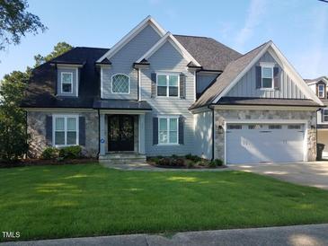 Charming two-story home with gray shingles, stone accents, a well-manicured lawn, and an attached two-car garage at 721 Shelley Rd, Raleigh, NC 27609