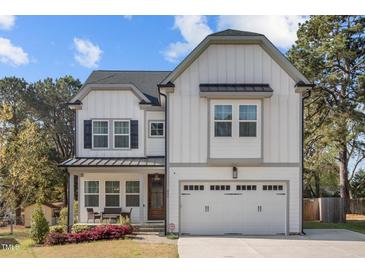 Charming two-story home featuring white board and batten siding and a two-car garage at 802 Knollwood Dr, Apex, NC 27502