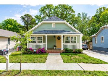 Charming home featuring a welcoming front porch, complemented by lush landscaping and a well-maintained lawn at 1023 Kent St, Durham, NC 27707