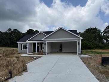 New home with gray siding, black roof, open garage, and concrete driveway at 107 Tee Dr, Selma, NC 27576