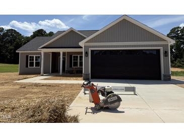 New construction home showing a spacious two-car garage with gray siding and a well-manicured lawn at 107 Tee Dr, Selma, NC 27576