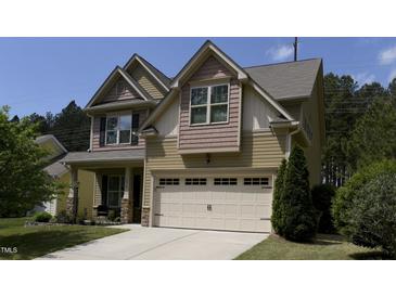 Charming two-story home with a light yellow exterior, complemented by a well-maintained front lawn and attached garage at 2012 Longmont Dr, Wake Forest, NC 27587