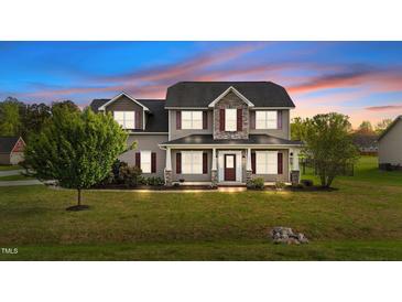 Charming two-story home features a covered front porch and well-manicured lawn, creating an inviting curb appeal at 24 Kaki Ct, Selma, NC 27576