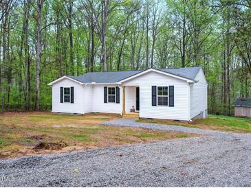 Charming single-story home with white siding, black shutters, and a gravel driveway nestled in a wooded setting at 25 Beechnut Ct, Franklinton, NC 27525