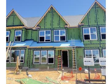 Townhome under construction showcasing windows, green weather barrier, and ladders against a bright blue sky at 3020 White Rail Dr, Fuquay Varina, NC 27526