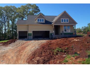 Unfinished two-story home featuring a three-car garage and dormer windows, set against a clear blue sky at 4897 Grosbeak Ct, Mebane, NC 27302