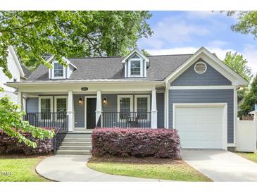 Charming home exterior with blue siding, covered front porch, manicured shrubs, and attached one-car garage at 604 Mills St, Raleigh, NC 27608