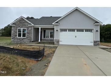 New construction home featuring gray siding, stone accents, and a two-car garage at 69 Tee Dr, Selma, NC 27576