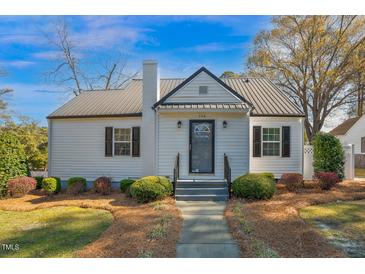 Charming home featuring a metal roof, white siding, and well-manicured landscaping at 708 W Pope St, Dunn, NC 28334