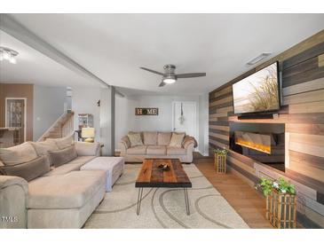 Cozy living room features a modern fireplace, ceiling fan, and comfortable seating area at 725 Ancient Oaks Dr, Holly Springs, NC 27540