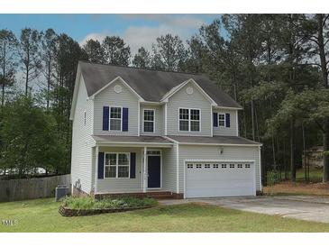 Charming two-story home featuring light siding, dark shutters, an attached two-car garage, and a well-maintained lawn at 910 Cedar Creek Dr, Wendell, NC 27591