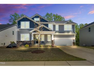 Charming two-story home with a two-car garage and manicured front yard at twilight at 105 Scoville Rd, Garner, NC 27529