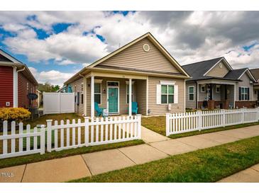 Charming single story home with a cozy front porch, white picket fence, and a welcoming blue front door at 110 Plott Hound Dr, Clayton, NC 27520