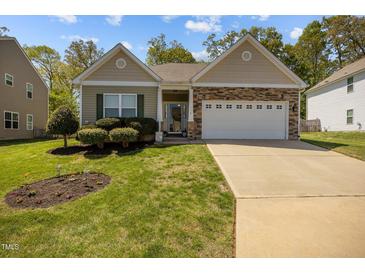 Charming single-story home features a two-car garage, stone accents, and beautifully landscaped front yard at 112 Pink Dogwood Ln, Mebane, NC 27302