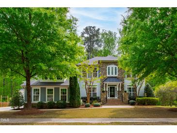 Charming two-story home features a stone and siding facade, lush landscaping, and a well-manicured lawn at 12833 Edsel Dr, Raleigh, NC 27613
