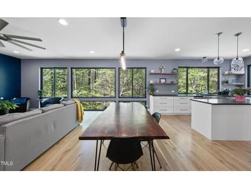 Open-concept living and dining area with scenic wooded views from large windows and hardwood flooring at 1401 Freshwater Ct, Wake Forest, NC 27587