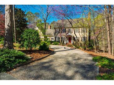 Charming two-story home with a gravel driveway, lush landscaping, and colorful trees in a peaceful setting at 213 Huntington Dr, Chapel Hill, NC 27514