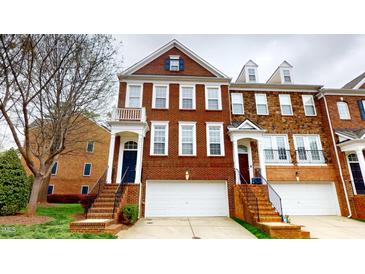 Brick townhome with attached garages, a covered entryway, and a stairway to the front door at 2750 Laurelcherry St, Raleigh, NC 27612