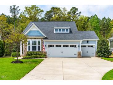 Charming home featuring a three-car garage, stone accents, and a well-manicured lawn at 408 Price Lake Way, Fuquay Varina, NC 27526