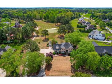 Beautiful home with manicured lawn overlooking the golf course in a lush, green community at 8409 Muirfield Dr, Fuquay Varina, NC 27526