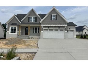 Charming two-story home with gray shake siding, a three-car garage, and unfinished front yard at 921 Lily Claire Ln, Fuquay Varina, NC 27526