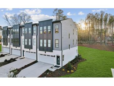 Modern townhome with gray siding, black accents, a driveway, and well-maintained landscaping at 10516 Pleasant Branch Dr # 34, Raleigh, NC 27614