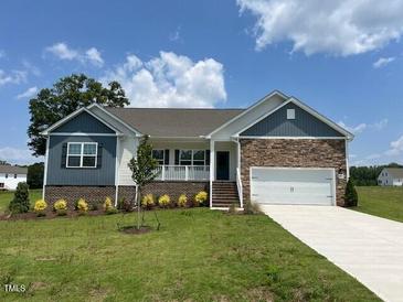 Charming single-story home featuring a manicured lawn, stone accents, and a two-car garage at 11470 International Dr, Middlesex, NC 27557