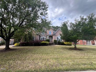 Charming two-story brick home with a well-manicured front lawn and mature trees at 222 Creststone Dr, Cary, NC 27519