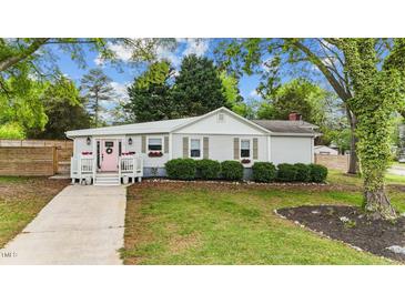 Charming single-story home featuring a pink front door and lush landscaping, creating a welcoming curb appeal at 703 E Horne St, Clayton, NC 27520