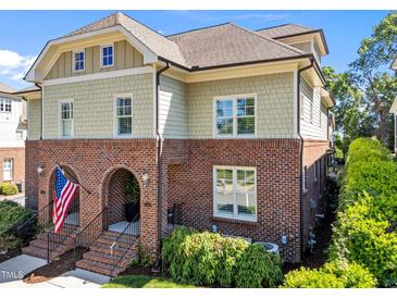 Beautiful townhome showcases classic brickwork, complemented by tan shingles and an inviting arched entrance, topped with an American flag at 714 Mordecai Towne Pl, Raleigh, NC 27604
