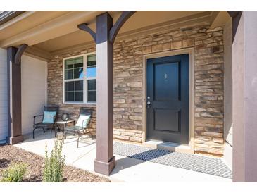 Inviting front door with a stone facade, covered entrance, and stylish welcome mat at 746 Wickham Ridge Rd, Apex, NC 27539