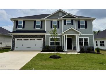 Two-story home with an attached two-car garage, a covered front porch, mature grass, and landscaped yard at 107 Southern Estates Dr, Sanford, NC 27330