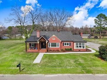 Charming brick home featuring a covered porch, manicured lawn, and classic architectural details at 305 E First St, Princeton, NC 27569