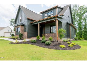 Beautiful two-story home with dark siding, brick accents, and well-manicured landscaping at 8620 Dukes Lake Rd, Zebulon, NC 27597