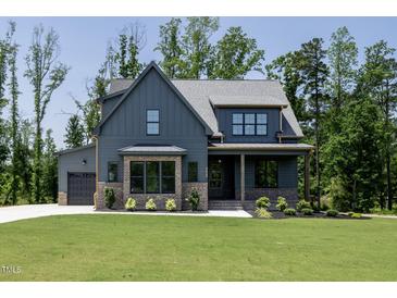 Craftsman home featuring a gray facade, manicured lawn and landscape, and attached garage at 8620 Dukes Lake Rd, Zebulon, NC 27597